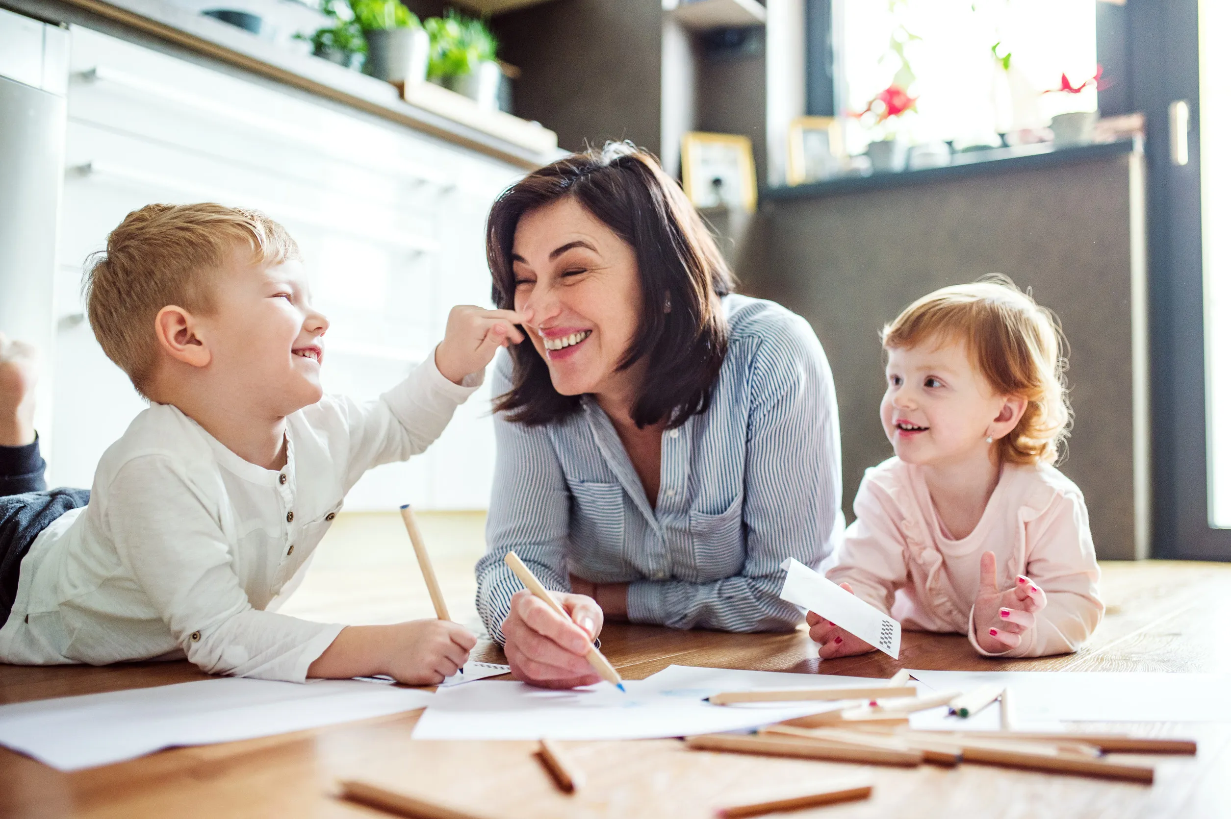 Grandma takes care of the grandchildren while their parents are at work, doing crafts, drawing on paper on floor